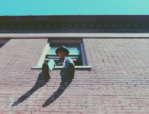 low angle photography of man sitting on window during daytime thumbnail